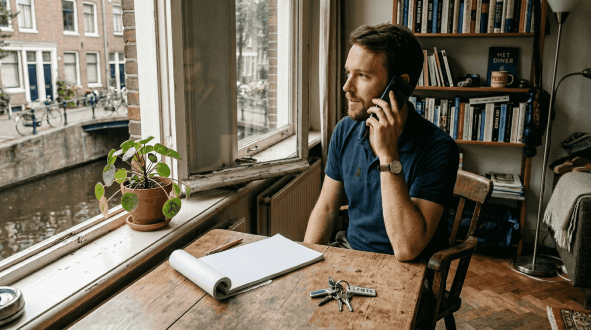 Een man zit aan zijn bureau en voert een telefoongesprek op zijn mobiel.