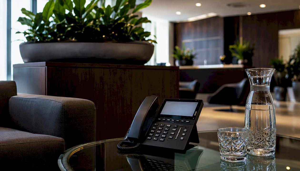 Een bureau met een vaste telefoon en stapels zakelijke papieren.
