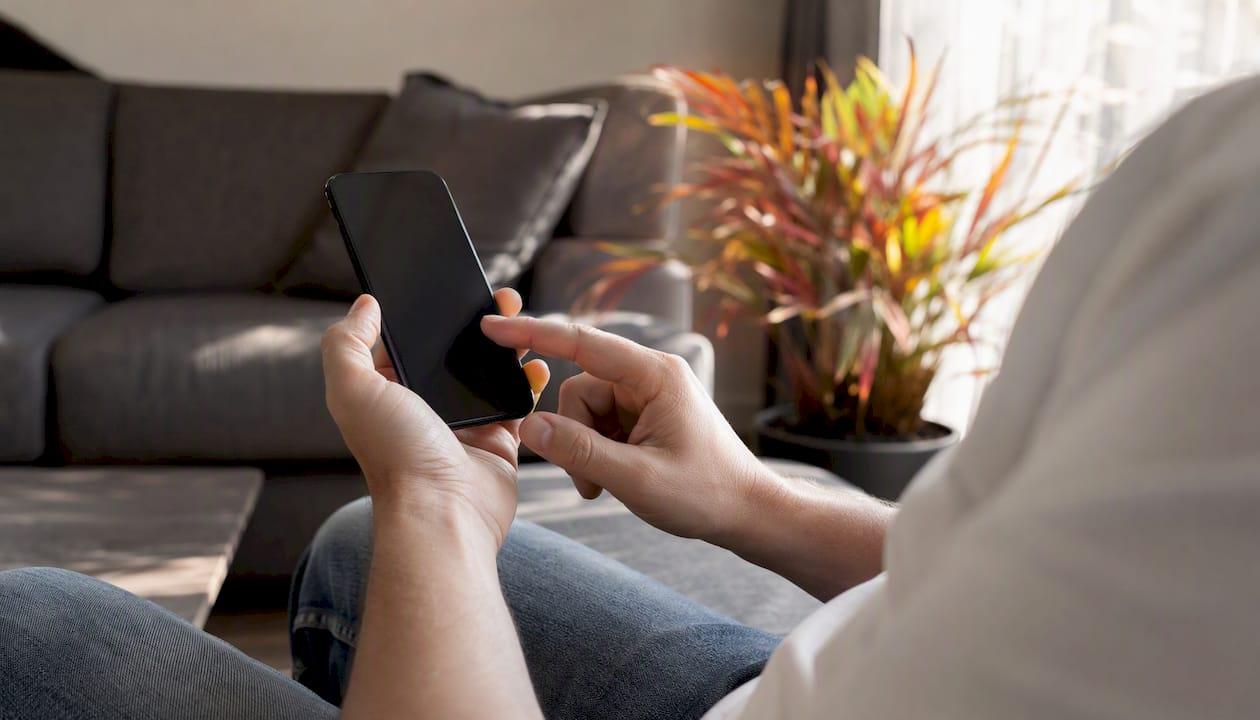 Detailopname van handen die een telefoonnummer intoetsen op een smartphone.