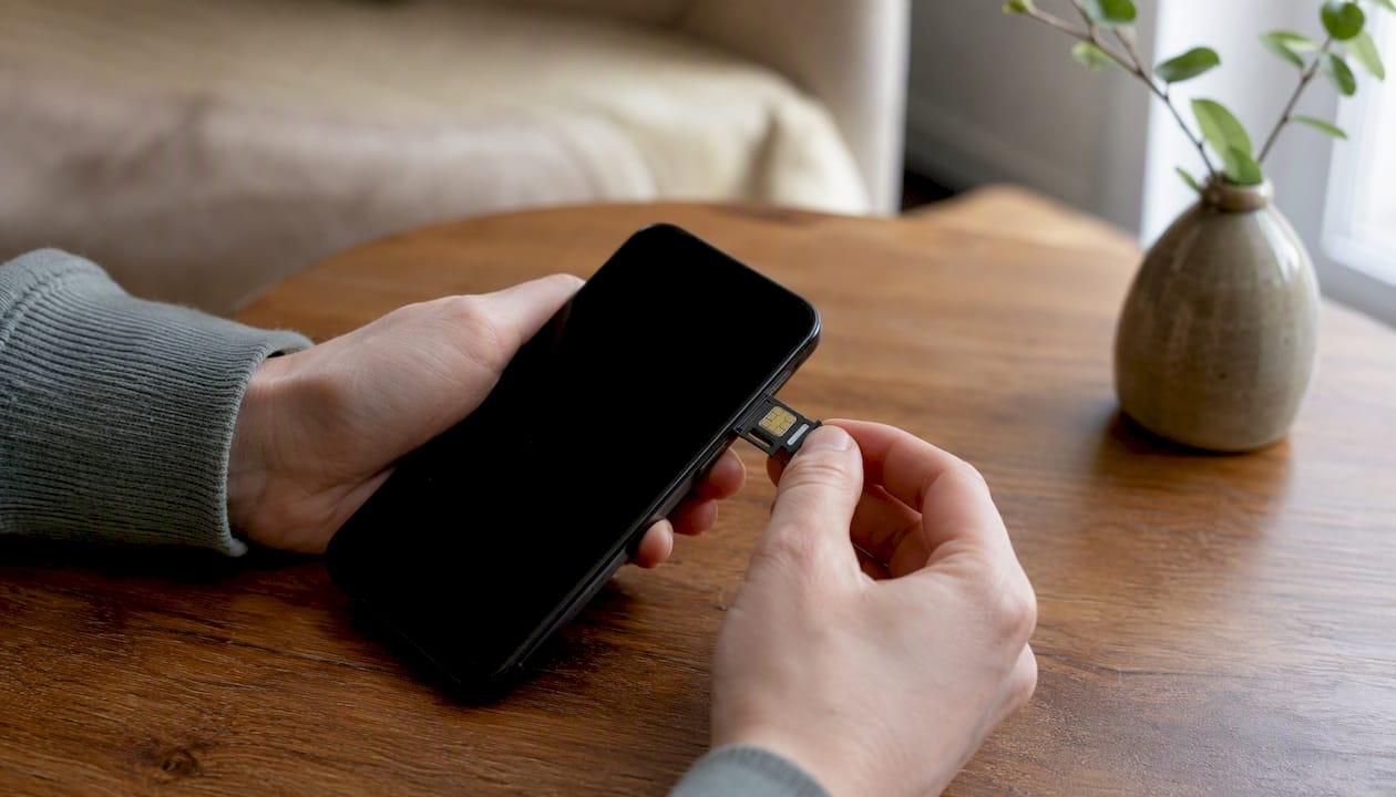 Een paar handen die een eSIM op een smartphone installeren.